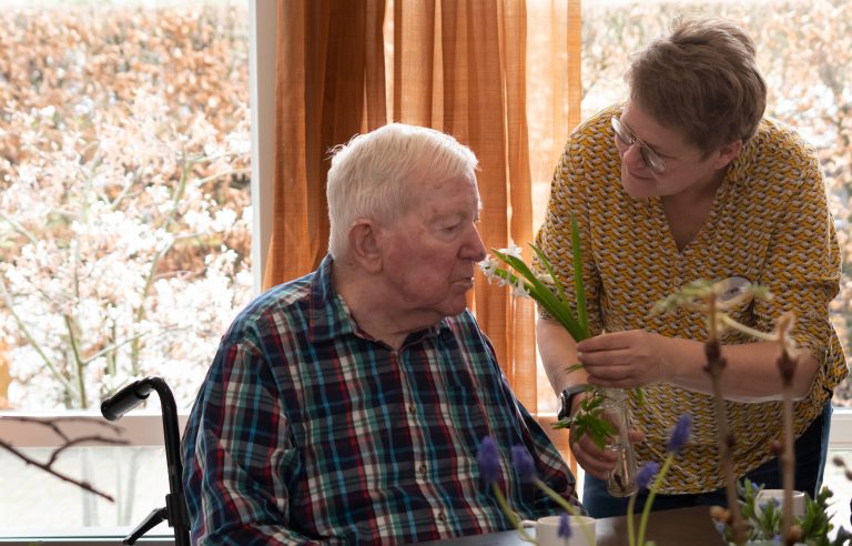 Oudere man in verzorgingstehuis ruikt aan bloem uit Natuurkoffer